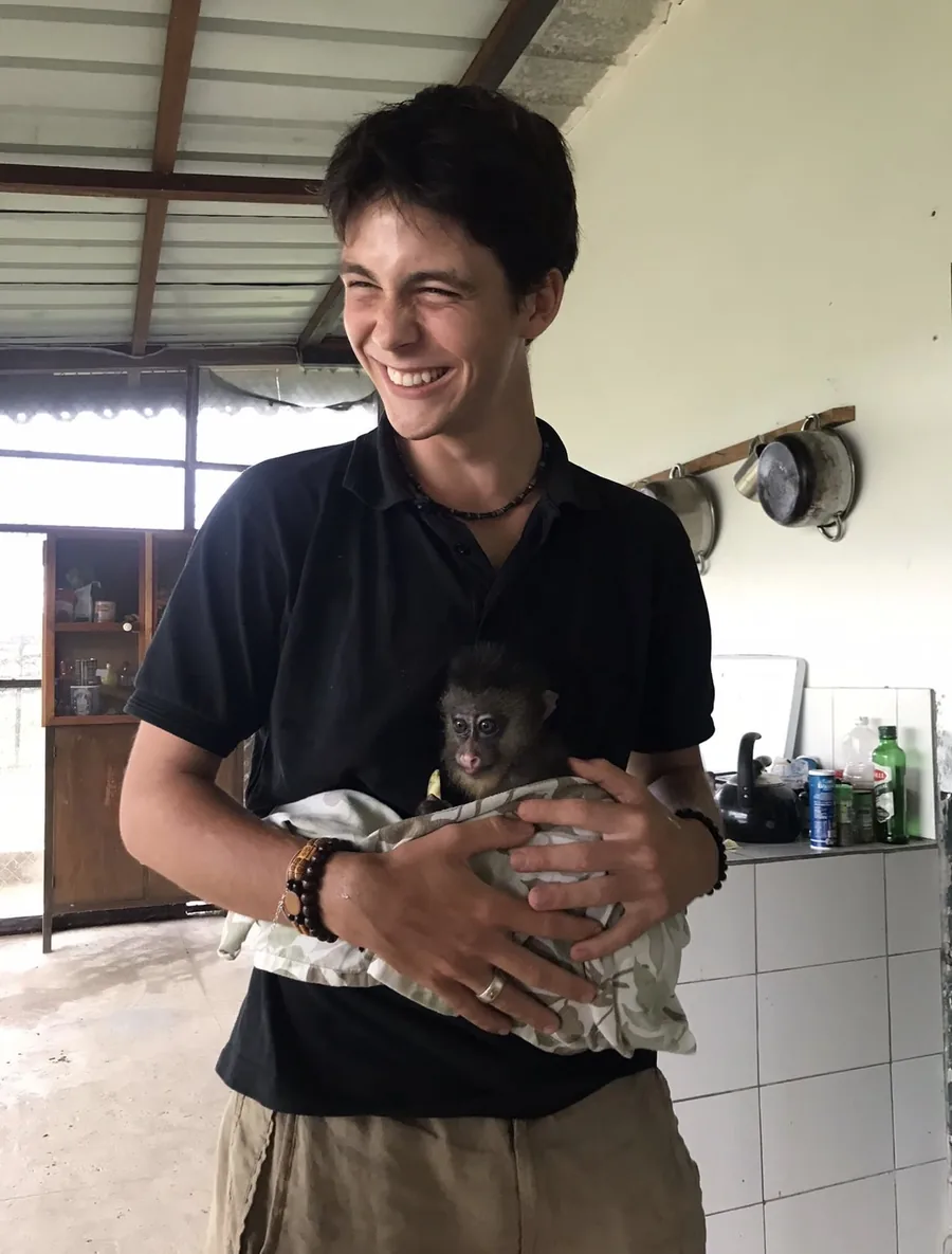 Guillaume smiling and holding a baby mandrill